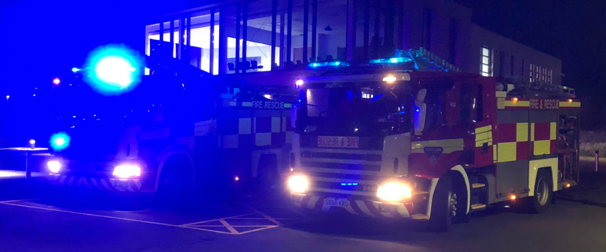 fire engines with blue lights outside of the headquarters taken at night