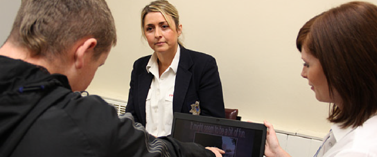 A female member of staff in old uniform talking to a young person about the dangers of firesetting