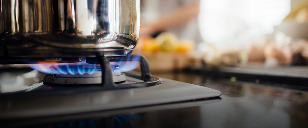 A gas hob turned on with a flame with a pan cooking food