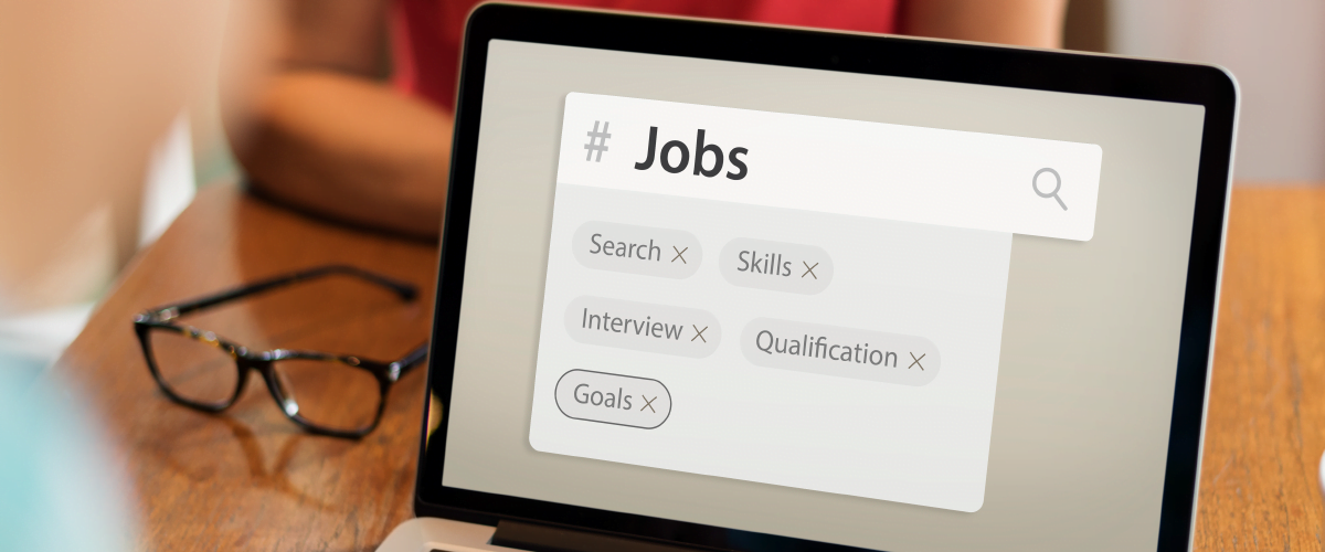 A laptop on a table with a screen showing a job search. Reading glasses can also be found on the table.