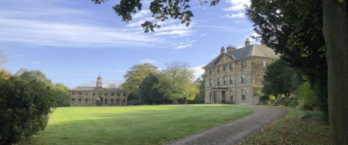 An image of a two heritage buildings surrounded by greenery and trees
