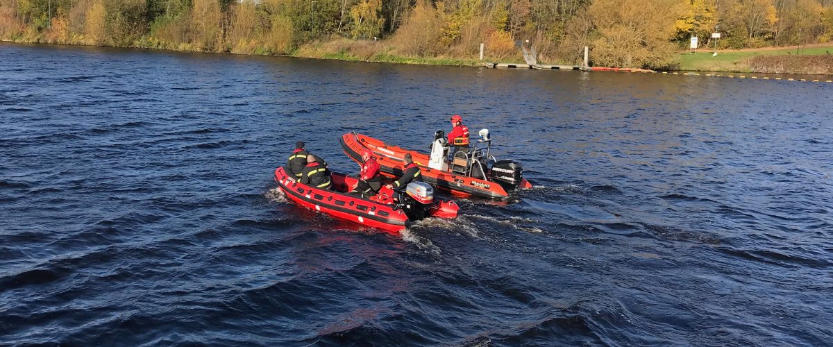 Firefighters in two red boats on a large body of water