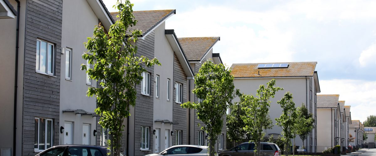 A row of modern new build houses with cars parked on the driveway