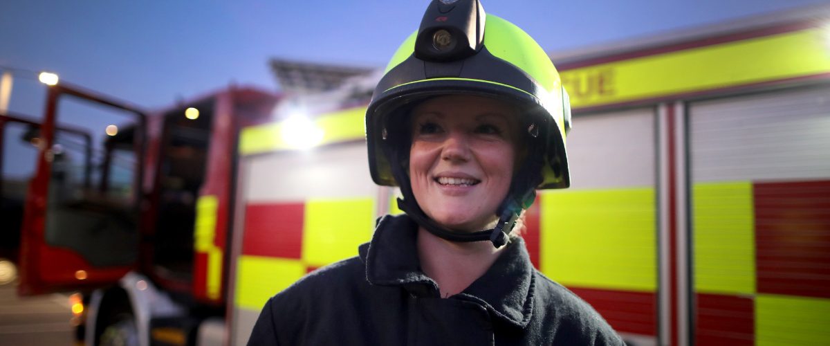 Female on-call firefighter in uniform stood in front of one of our fire engines