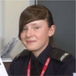 a young girl with brown hair wearing navy blue uniform with a red lanyard