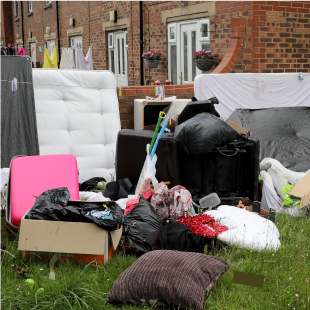 flytipping comprising of rubbish and a mattress outside of a house