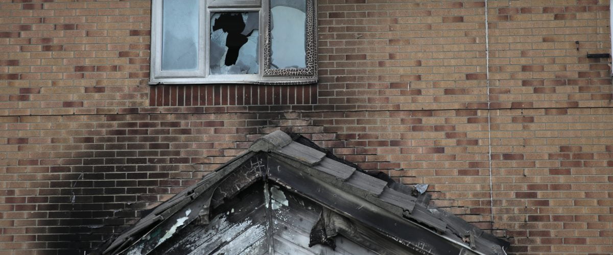 A house which shows damage from arson. Black remains on the brick work, window and a smashed window.