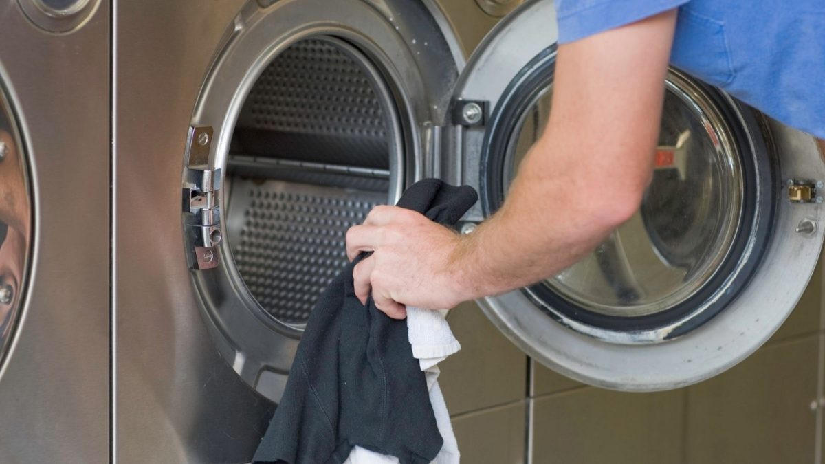 a person putting some clothes into a washing machine