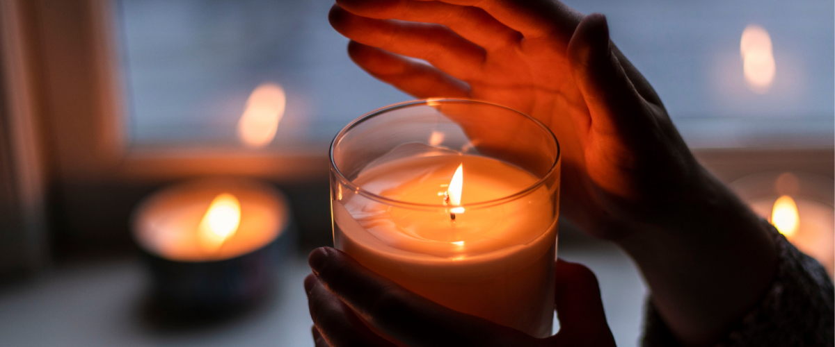 A pair of hands carrying a lit candle