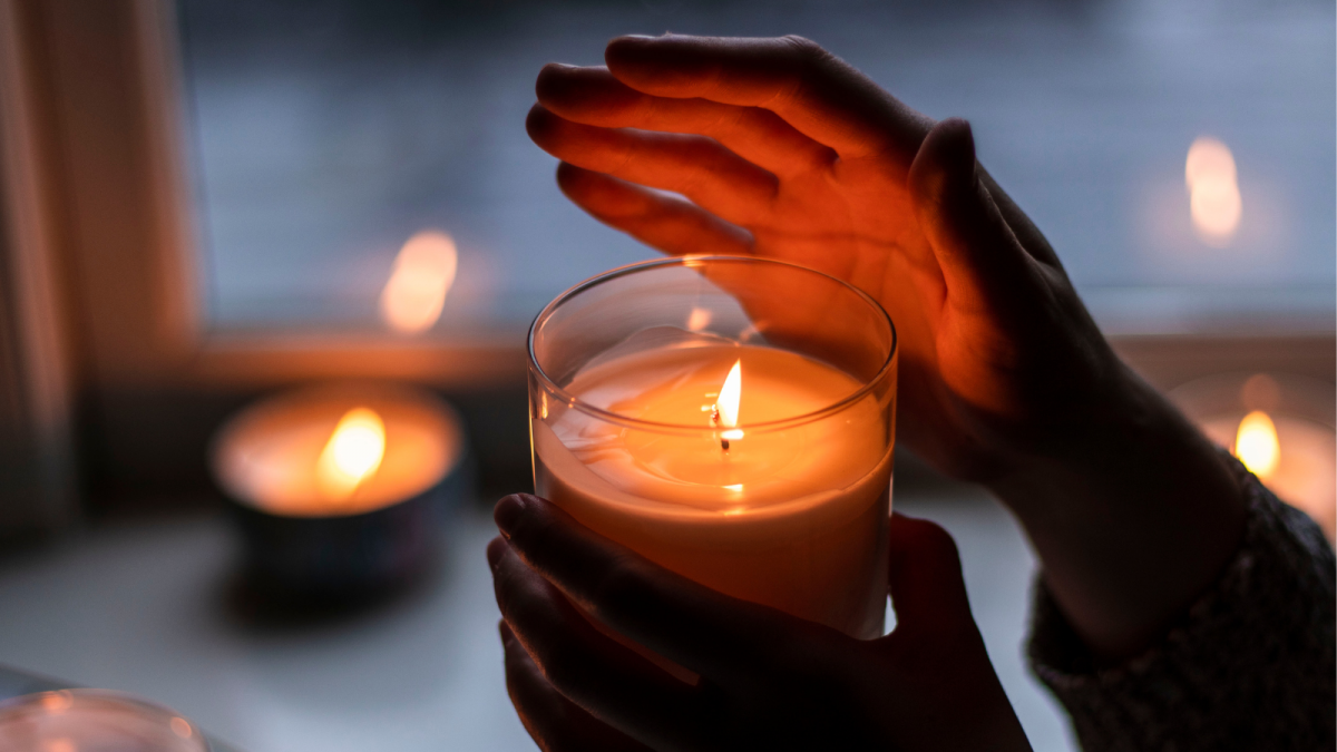 A pair of hands carrying a lit candle