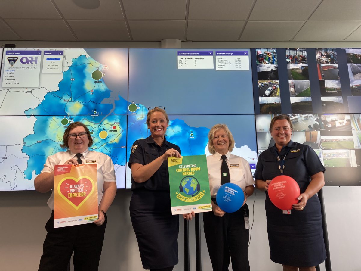 Four ladies holding posters and balloons in the control room celebrating Control Room Week