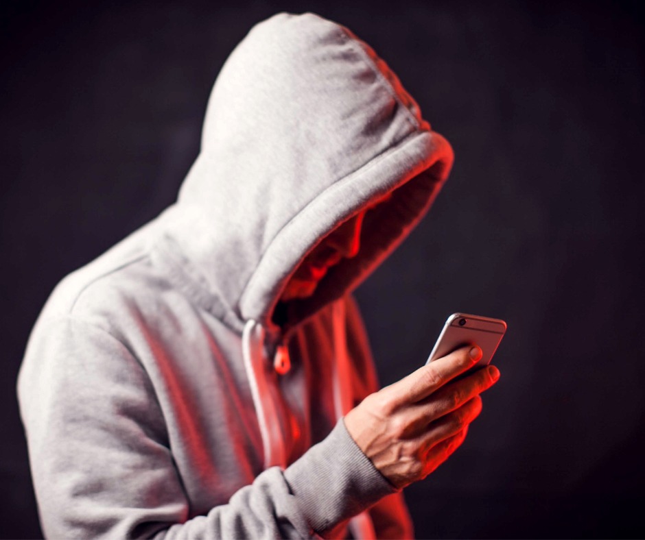 An image showing a young man with his hood up using his mobile phone