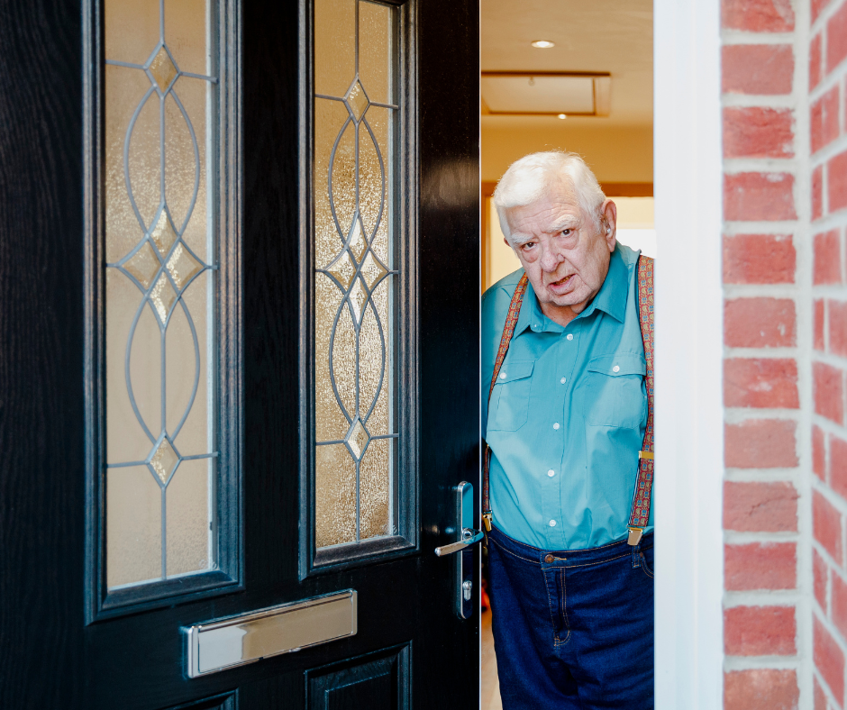 An older gentleman opening the front door of his home.