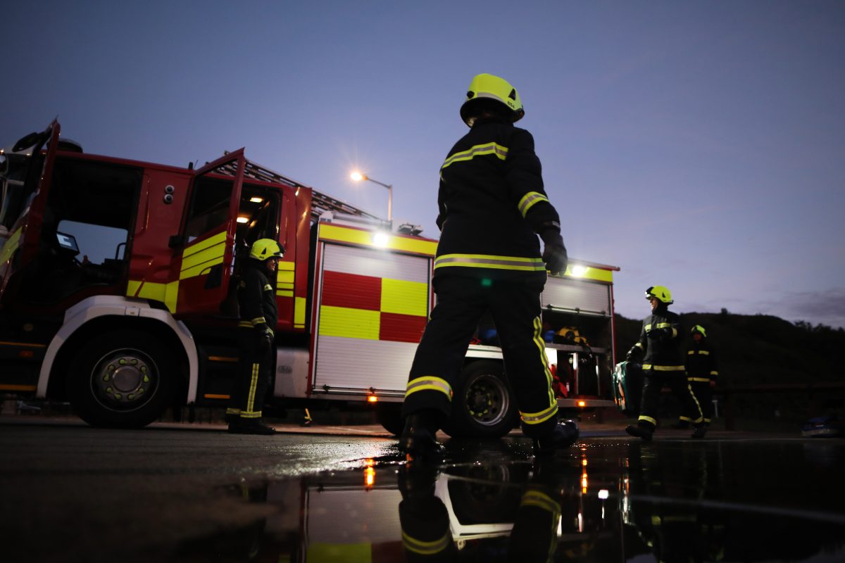 A picture of firefighters and a fire engine at night