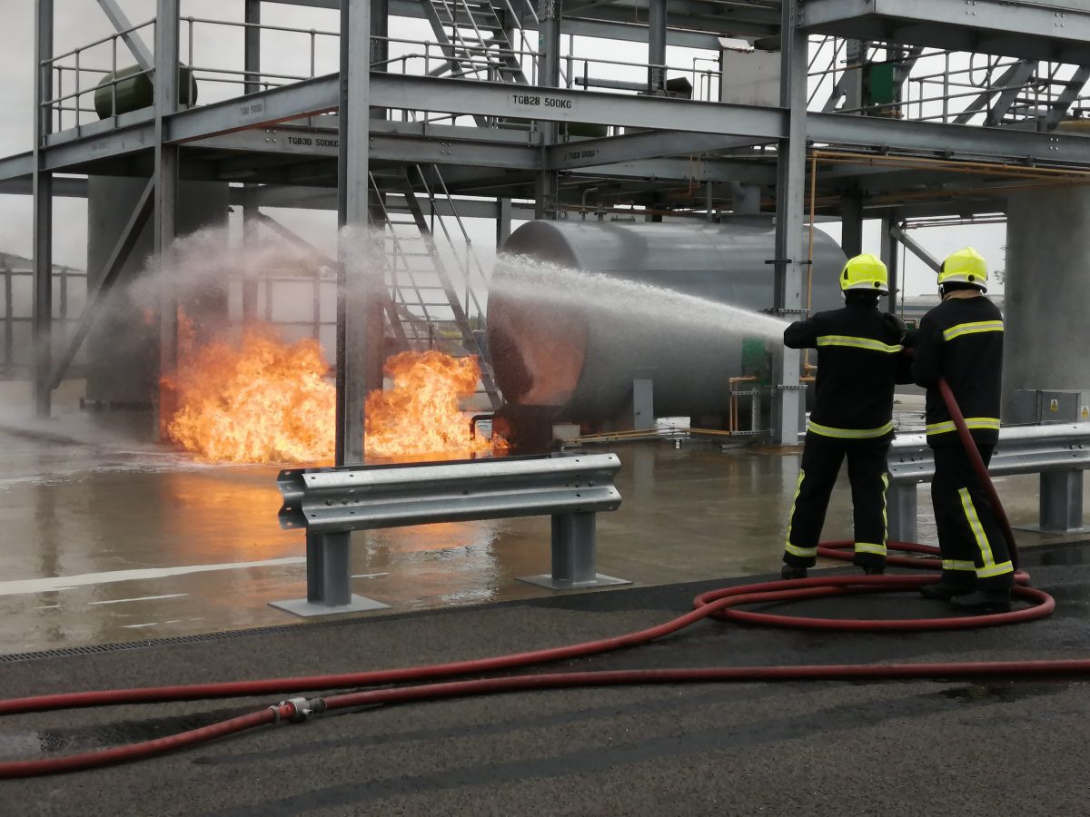 Two firemen using a hose to extinguish a fire