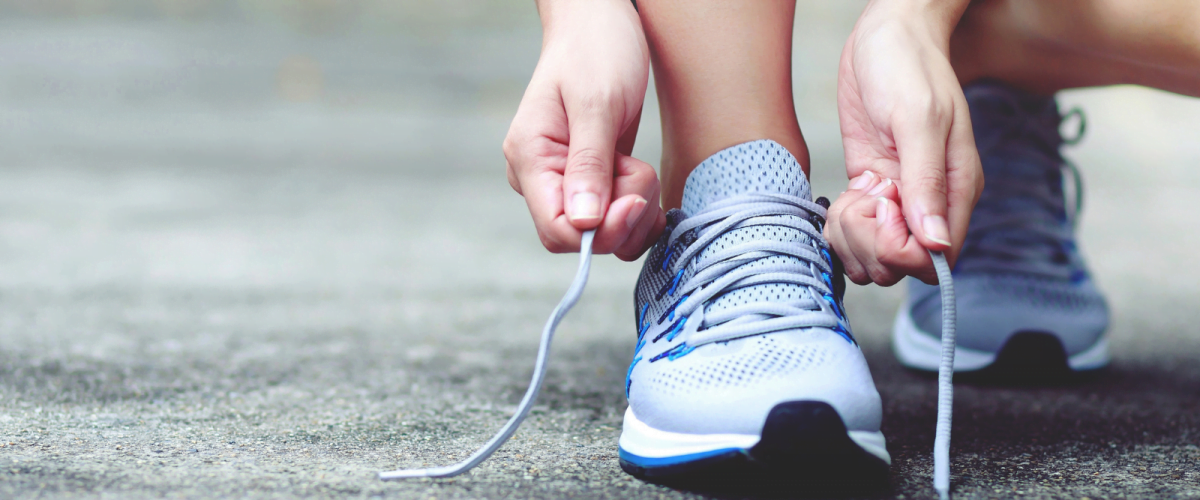 a person bending down to fasten laces on trainers