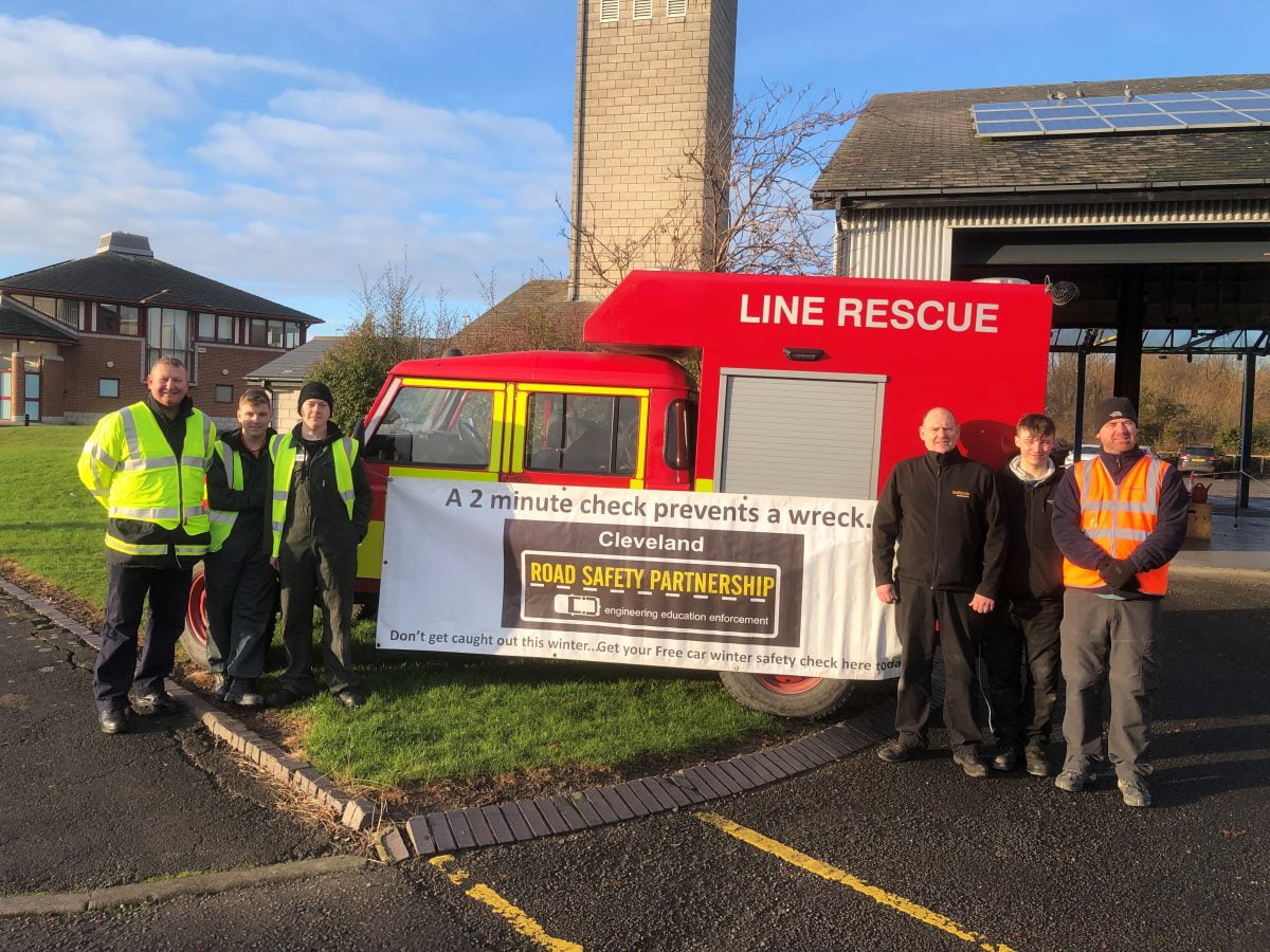 Line rescue vehicle with a banner and members of staff in uniform stood next to