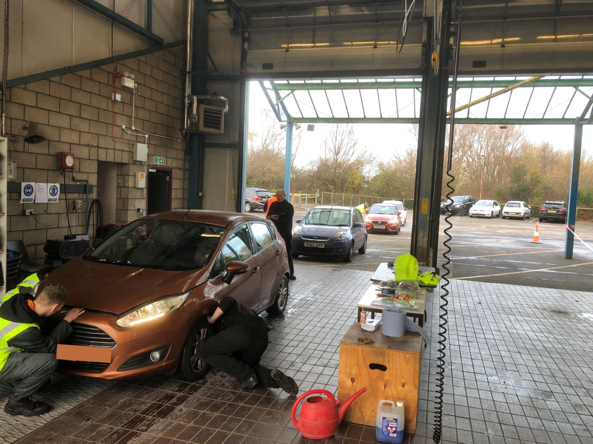 A bronze car getting fixed at a garage