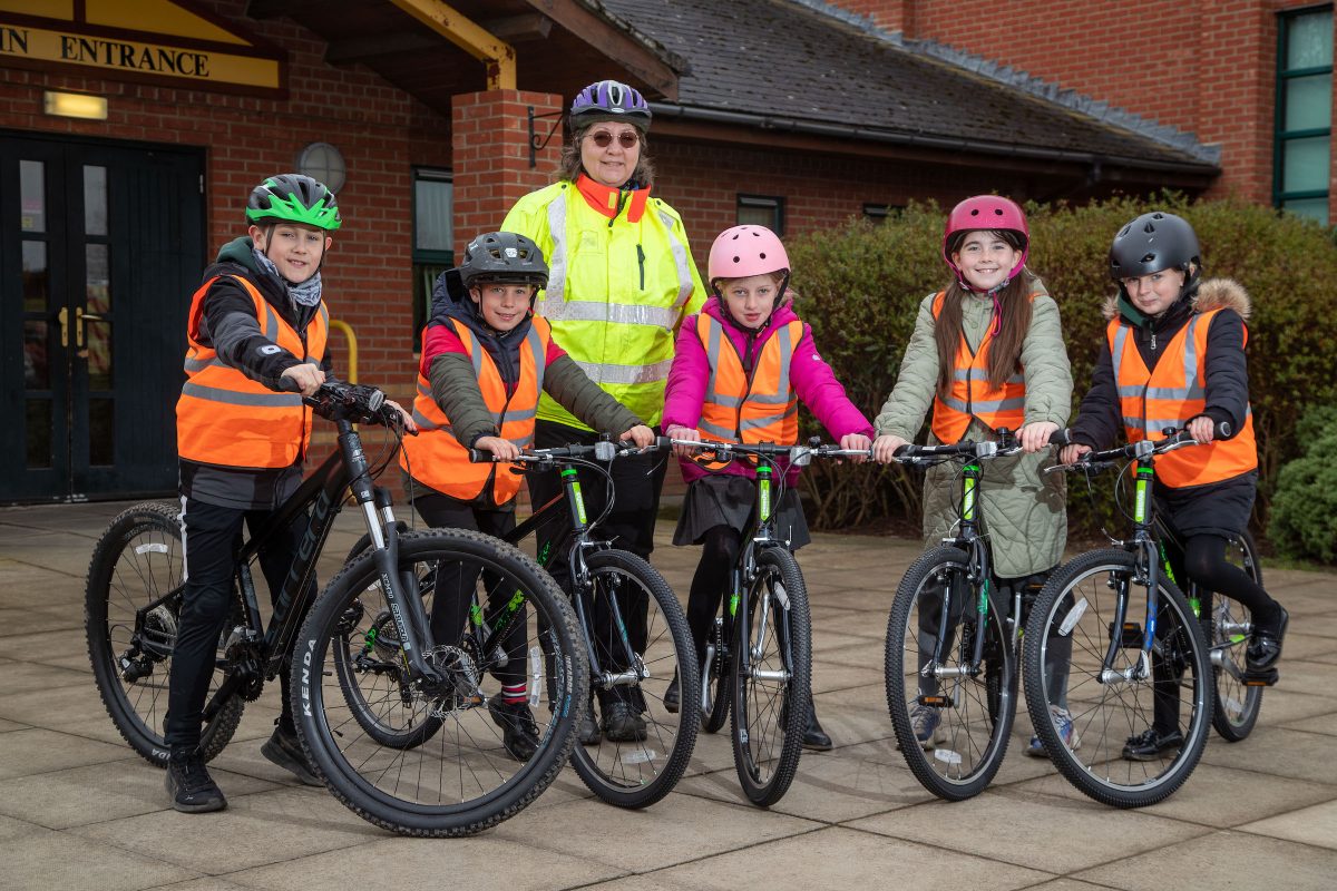 A group of school children on their bikes wearing high vis jackets
