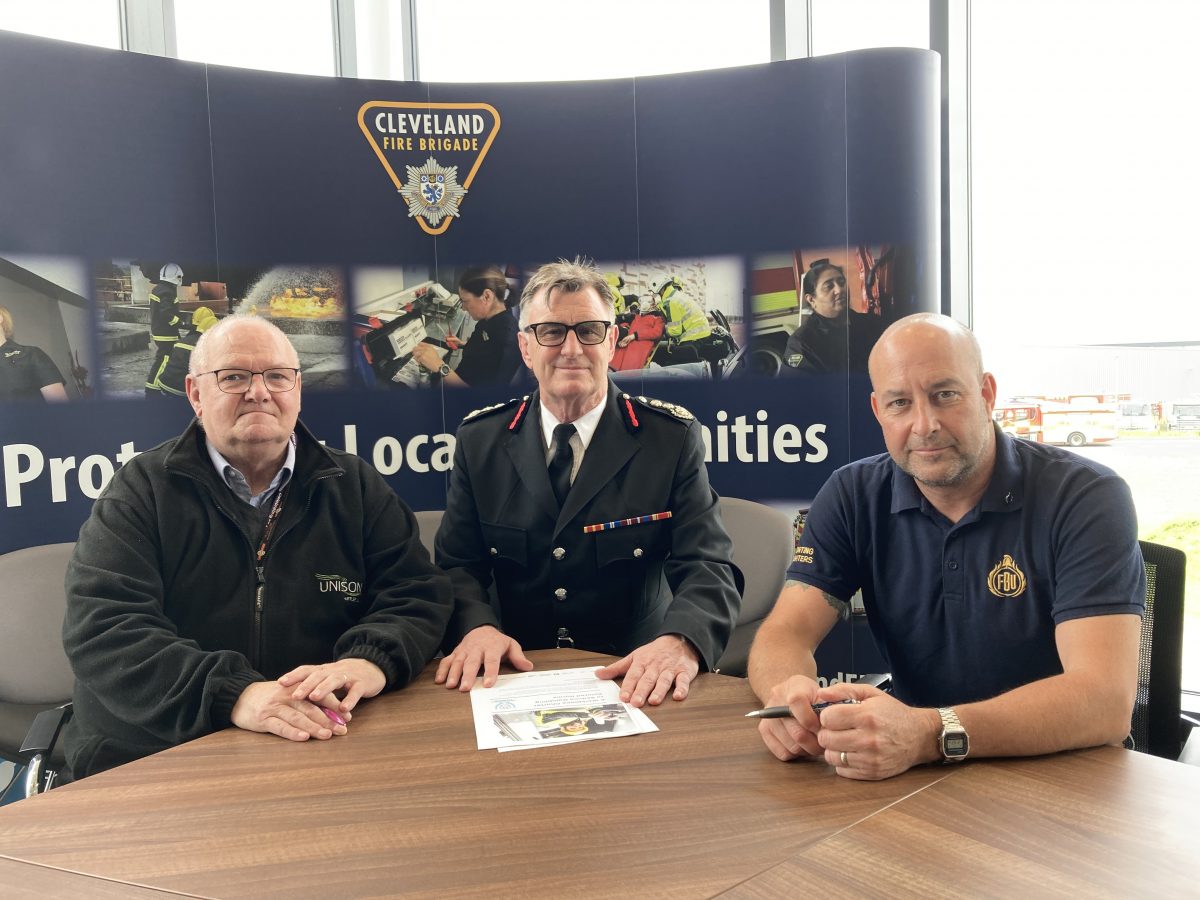 A picture showing three males sat around a table about to sign the gambling charter