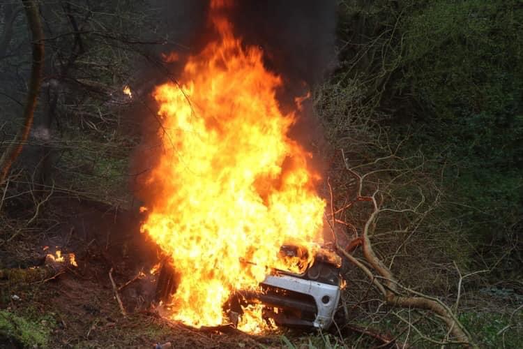 A vehicle fully ablaze in the woods