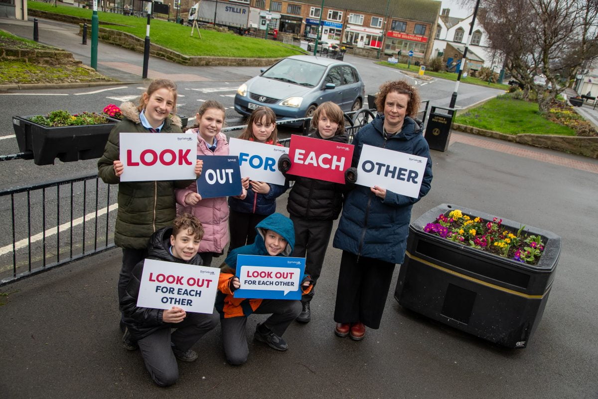 A group of school children and their Headteacher holding up anti speeding signs