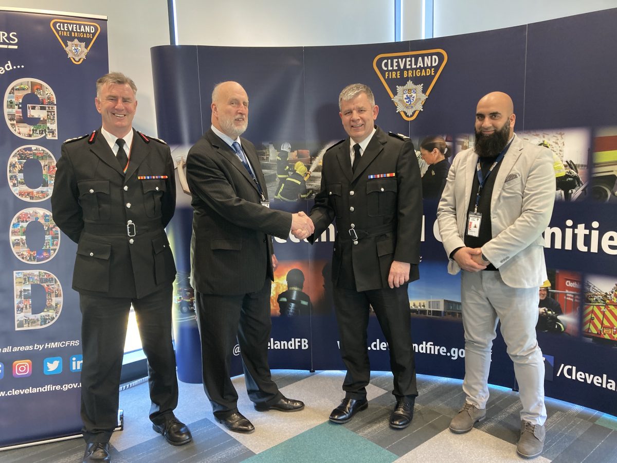 A photo showing four men and Simon being congratulated with a handshake by Chair of the Combined Fire Authority Cllr David Coupe. He is also joined by Chief Fire Officer Ian Hayton and Vice-Chair Cllr Sufi Mubeen.