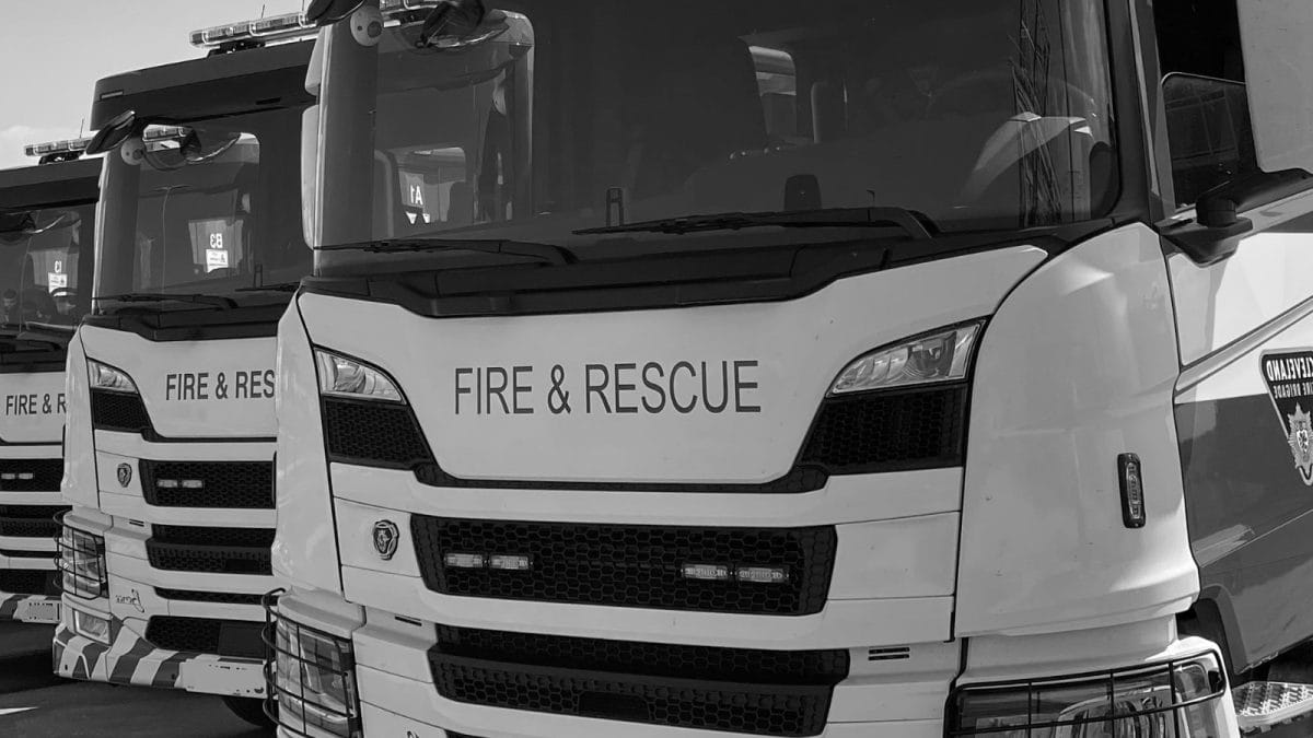 A picture of the front of three fire engines close up in black and white.