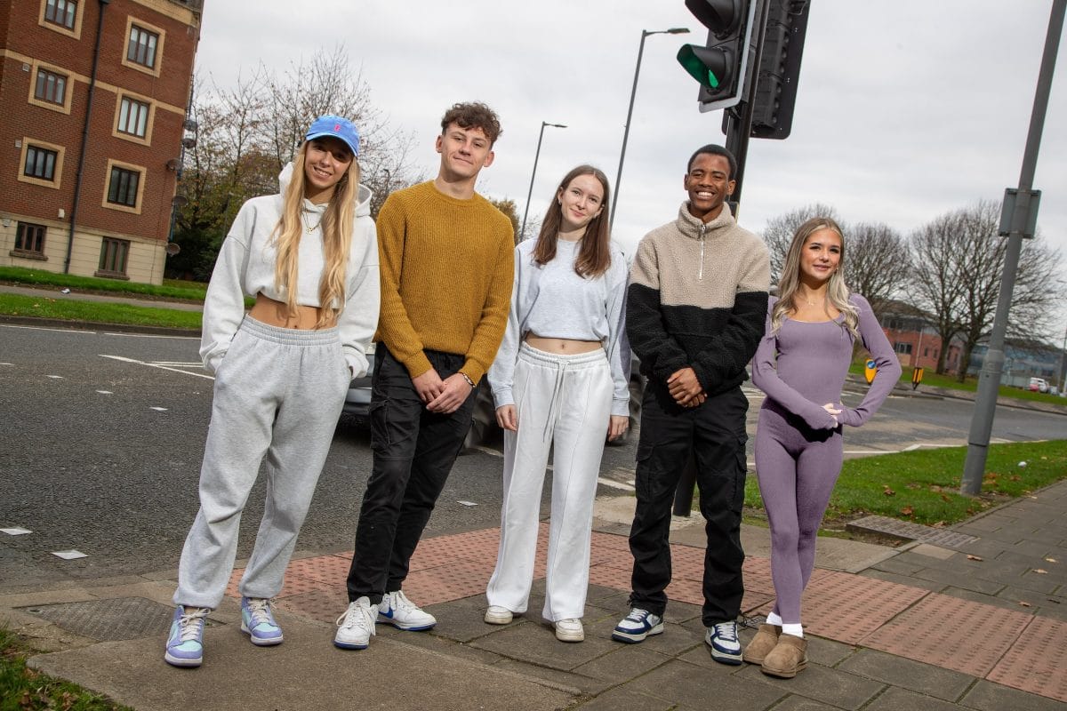 Five students stood on a pavement near a traffic light.